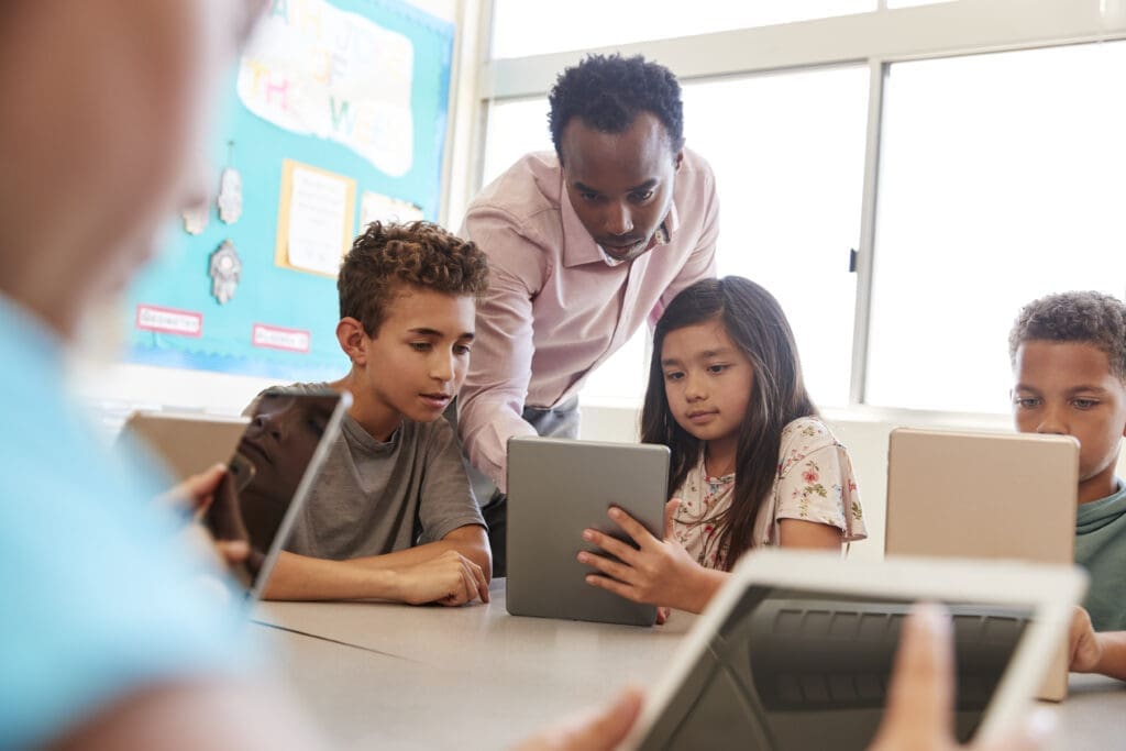 Teacher among school kids using computers in class